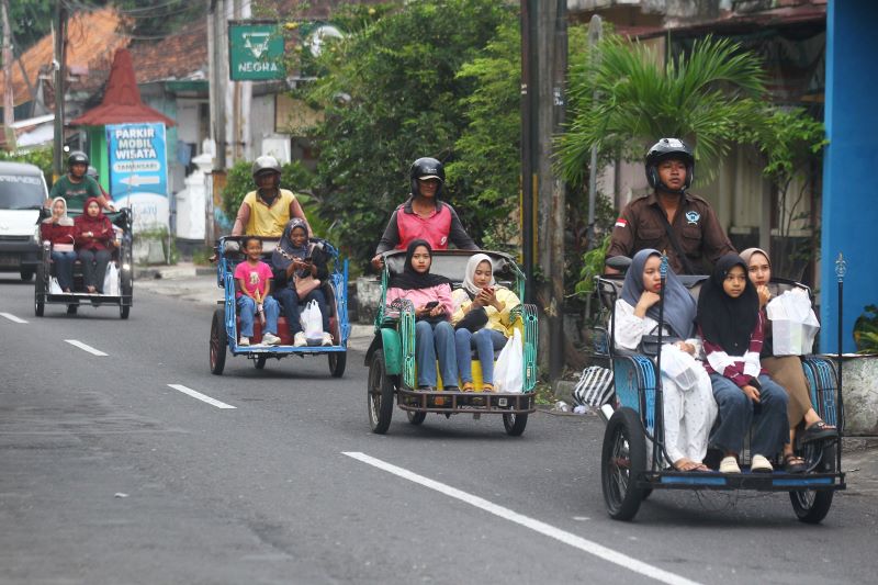 Pengemudi becak motor mengantar wisatawan berkeliling saat melintas di kawasan Ngasem, Kota Jogja Minggu (15/6)