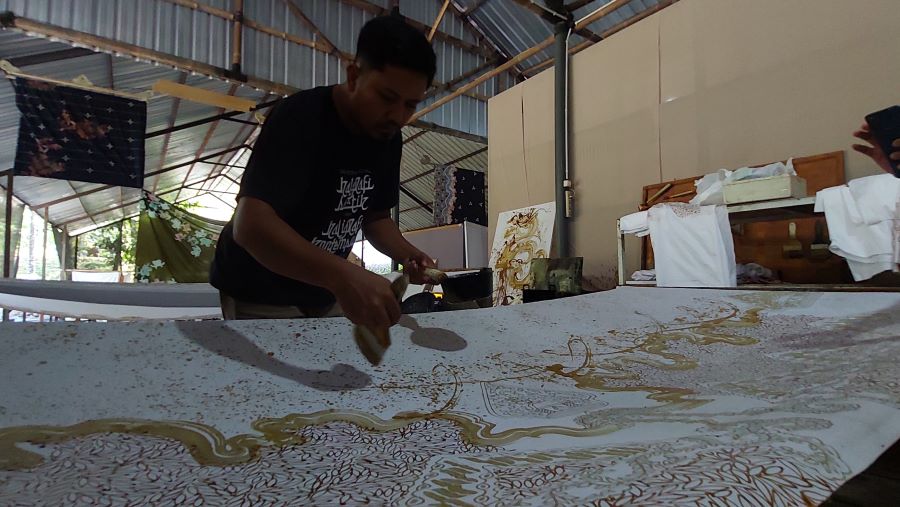 PEMBUATAN: Hanang mengoleskan malam panas pada batik bermotif gunungan wayang.
