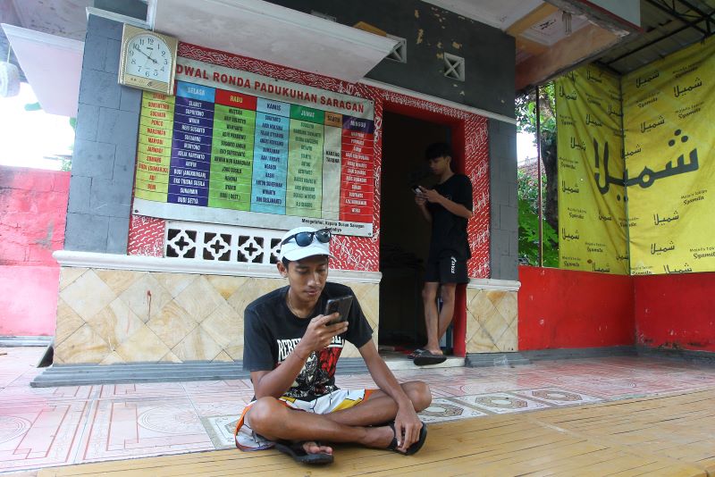TERBATAS: Warga mengakses internet menggunakan gawai di pos ronda Padukuhan Soragan, Pandowoharjo, Sleman Senin (23/6).