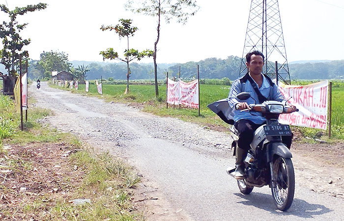 SOLUSI SEMENTARA: Warga Kalurahan Srikayangan melewati jalan yang telah ditambal dengan tanah urug.&nbsp;
