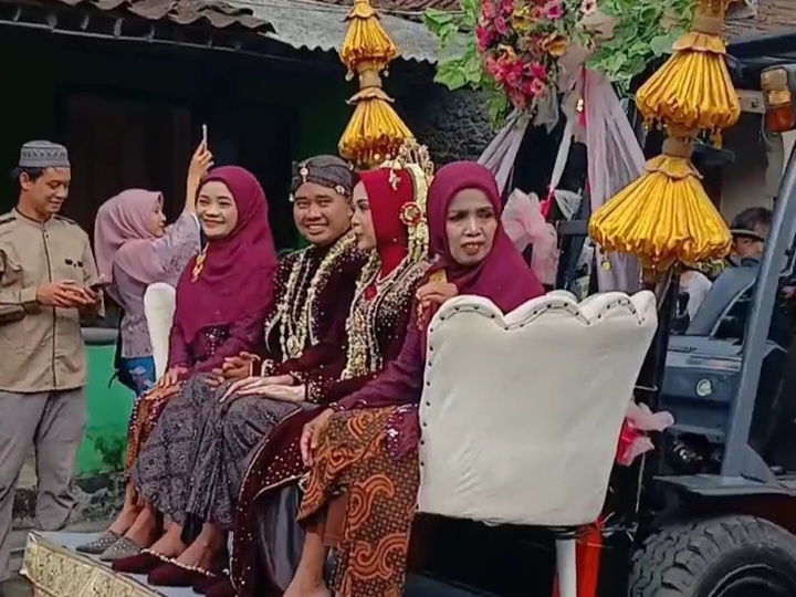 Pasangan pengantin Asep dan Khapsoh duduk di forklift didampingi ibunya saat diarak untuk prosesi ngunduh mantu.