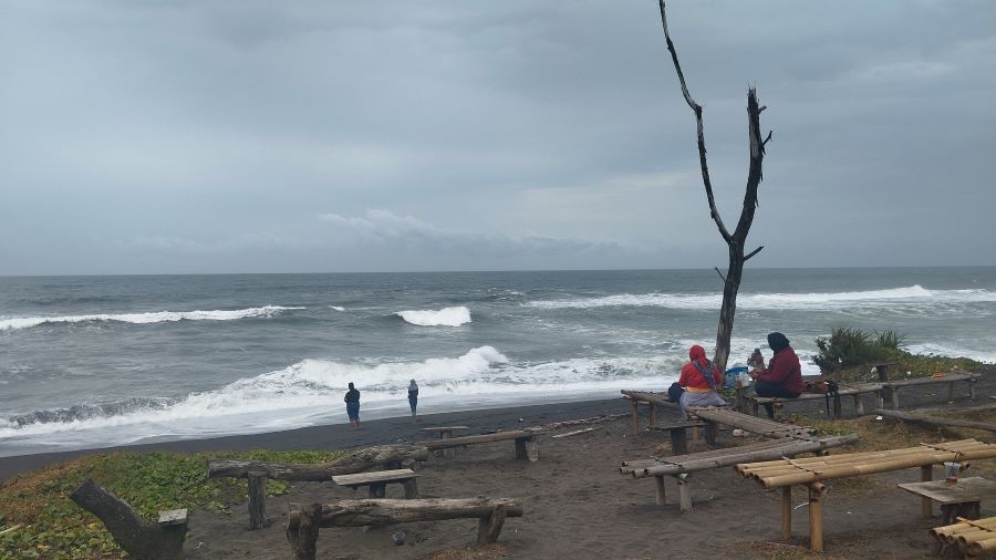 MENIKMATI: Wisatawan yang sedang duduk di Pantai Tanggul Tirto