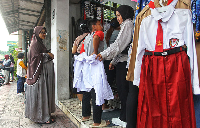 SERAGAM SEKOLAH: Orang tua menemani anaknya membeli seragam sekolah baru di toko perlengkapan  sekolah di Jalan Ibu Ruswo, Kota Jogja, Minggu (13/7/2025).