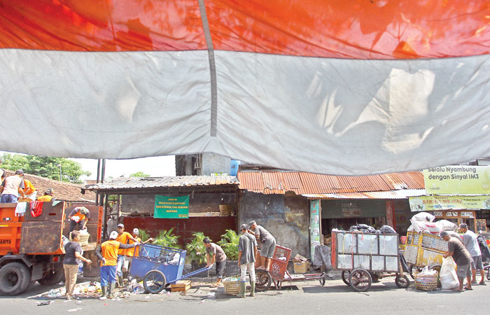 Petugas DLH Kota Jogja dengan menggunakan armada truk mengangkut sampah yang sudah dikumpulkan para penggerobak sampah, di depo kawasan Lempuyangan, Jogja, Senin (7/7).