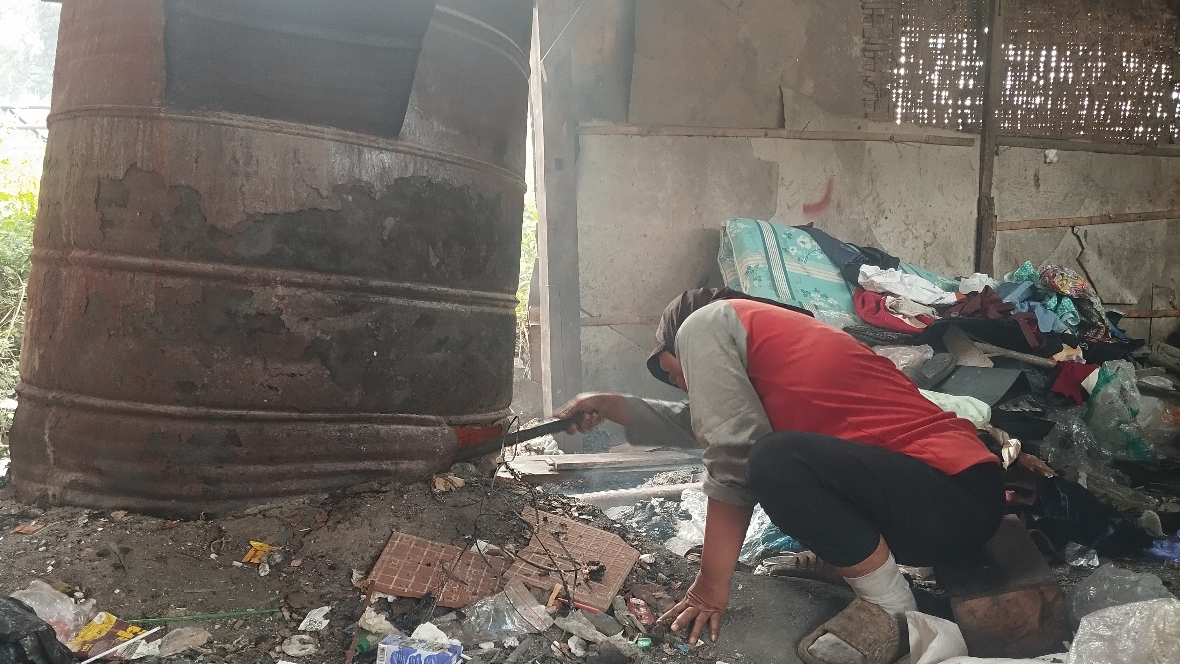Martini sedang mencongkel tungku tobong agar sampah yang ada di dalamnya bisa cepat terbakar Kamis (17/7)