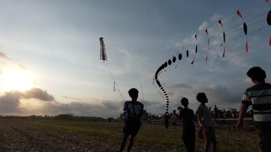 MUSIMAN: Warga sekitar menerbangkan layang-layang di atas sawah kering.