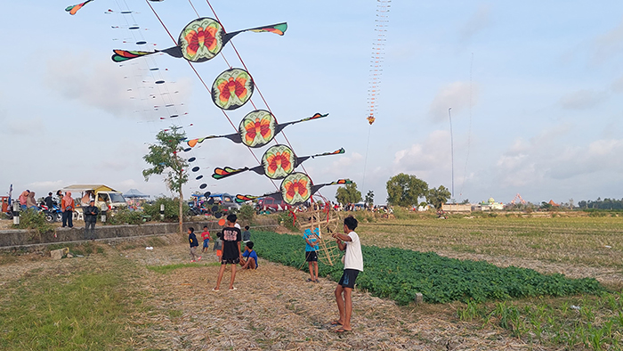 MUSIMAN: Warga sekitar menerbangkan layang-layang di atas sawah kering.
