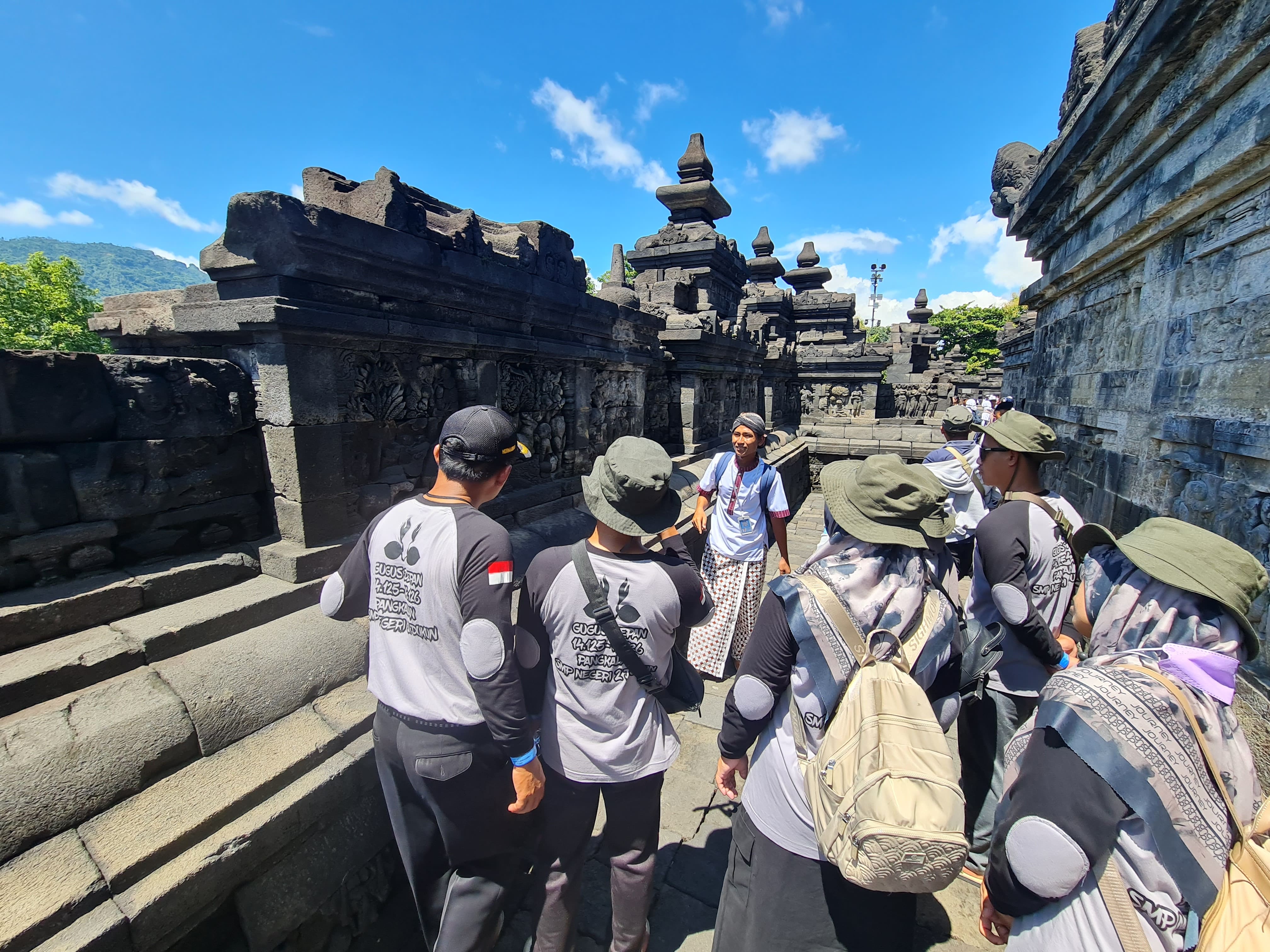 Pemandu wisata tampak menjelaskan struktur Candi Borobudur kepada wisatawan.