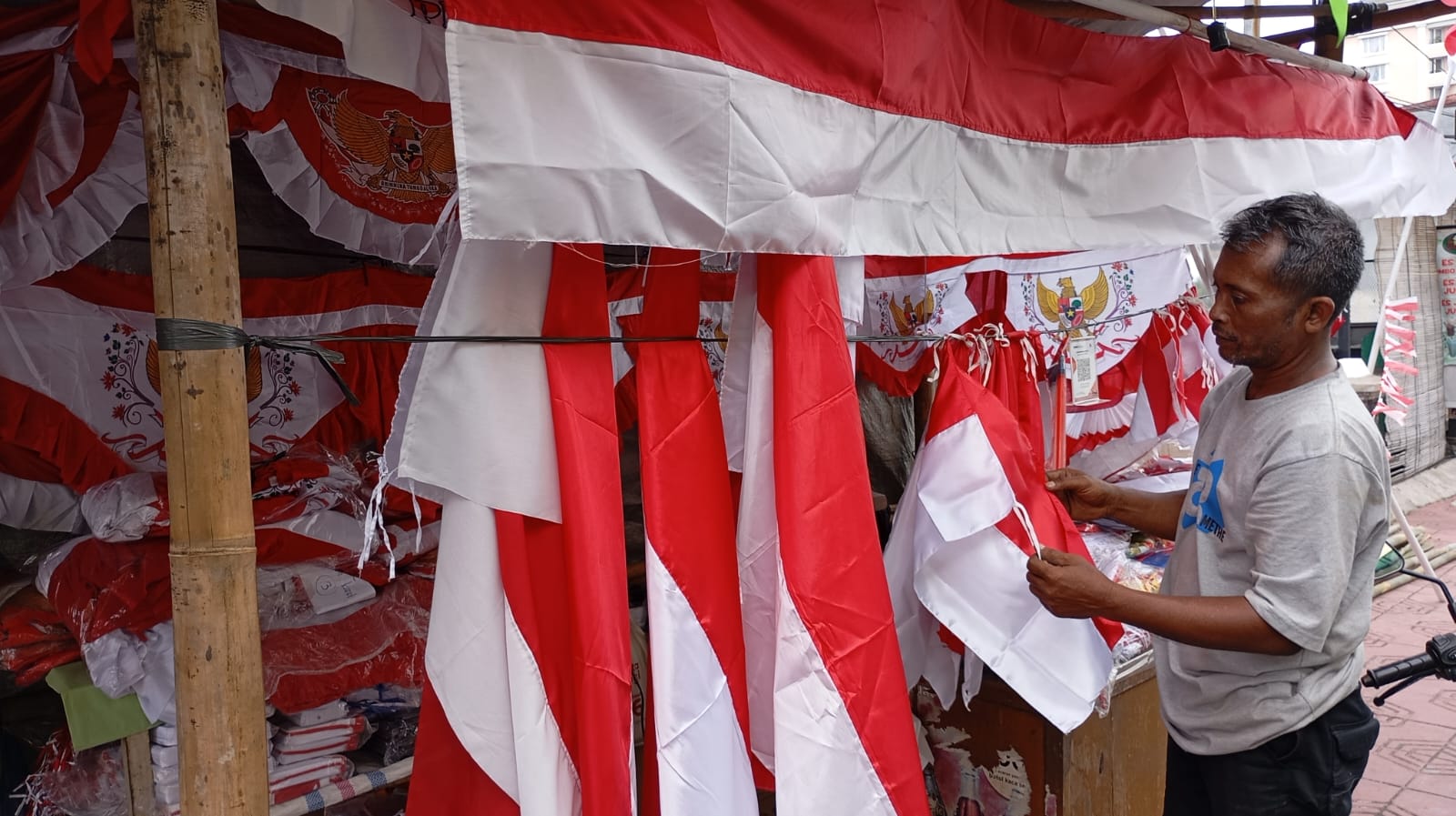 Salah satu pedagang bendera di Jalan Juminahan, Ngupasan, Gondomanan, Kota Jogja Ikhsanudin,48 saat menata bendera yang dijualnya pada Senin (4/8/2025).