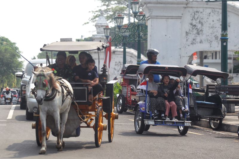 CIRI KHAS: Wisatawan menaiki andong dan becak motor saat melintas di seputaran kawasan Alun-Alun Utara, Jogja Selasa (5/8).