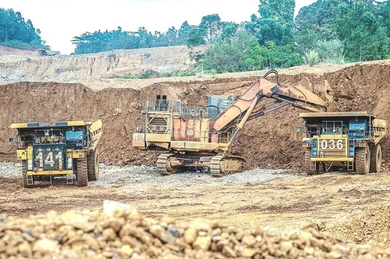 Ekskavator memindahkan tanah ke truk dalam pertambangan nikel di Sulawesi.