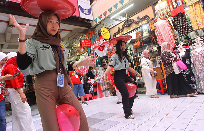 Pedagang mengikuti lomba menyunggi tampah sembari mengapit balon diantara kaki dalam rangka menyambut HUT Kemerdekaan RI ke-80, di Pasar Beringharjo sisi barat, Kota Jogja.