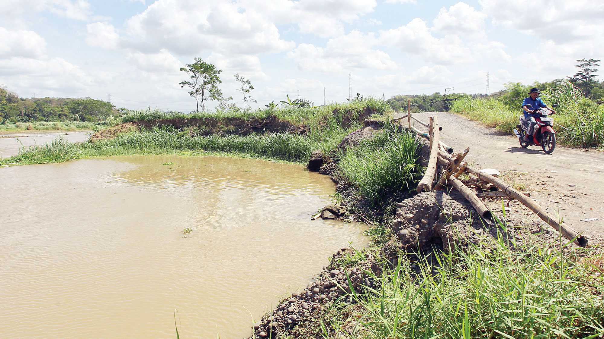 Warga melintas di dekat bekas galian tambang pasir di Sungai Progo wilayah Kabupaten Kulon Progo, kemarin (14/8).