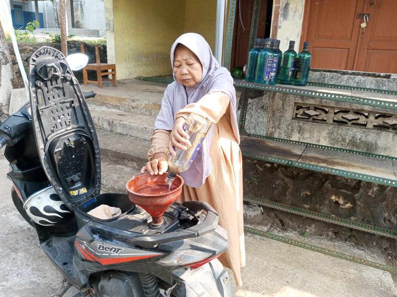 Marsim, penjual bensin eceran di dekat JJLS Paliyan sedang menuangkan bensin ke tangki sepeda motor pembeli Senin (18/8).