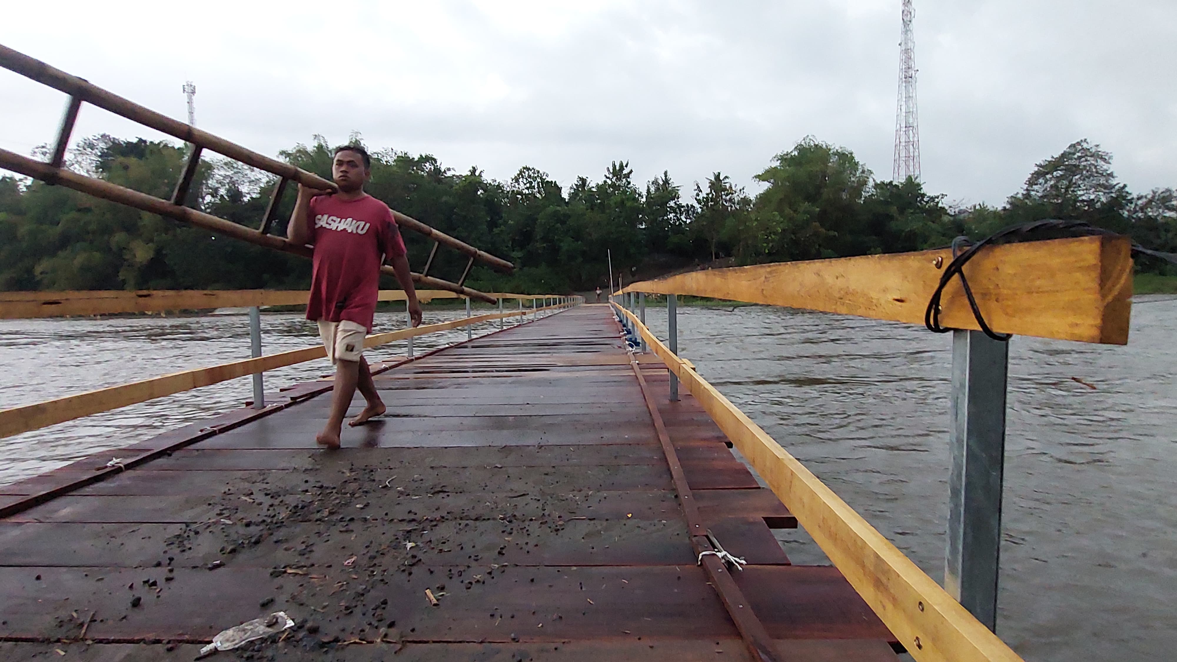 Masyarakat melewati jembatan apung saat air Sungai Progo Meluap