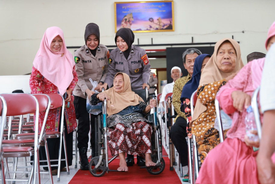 EMPATI: Dua polwan membantu lansia saat pemeriksaan kesehatan di Kalurahan Sumberrejo, Tempel, Sleman (20/8).