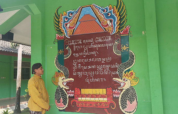 NGURI-URI: Guru Bahasa Jawa sedang melihat tulisan aksara Jawa yang ada di tembok SMPN 4 Banguntapan Kamis (21/8).