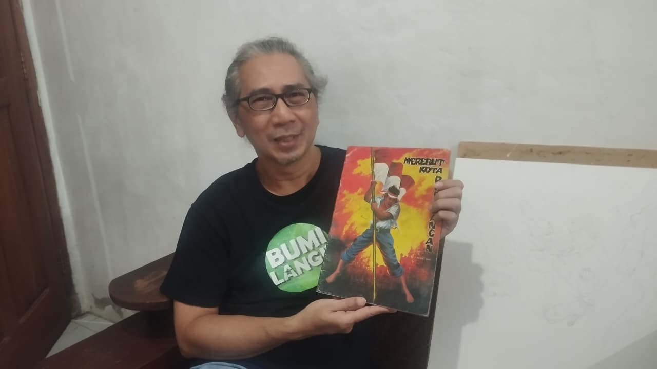 Putra Wid NS, Fajar Sungging sedang memegang komik Merebut Kota Perjuangan karya ayahnya Jumat (22/8/2025).