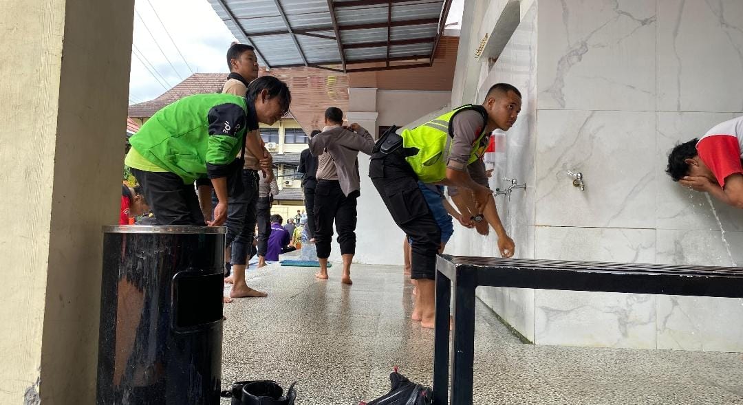 Petugas dan driver ojol mengambil air wudhu untuk salat ghaib di Mapolda DIY (19/8/2025).