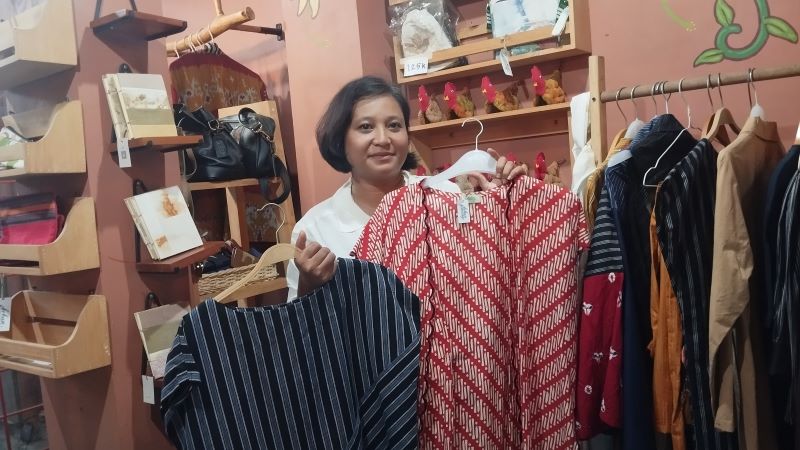 Rhodiah Safitri sedang memegang baju hasil desainnya