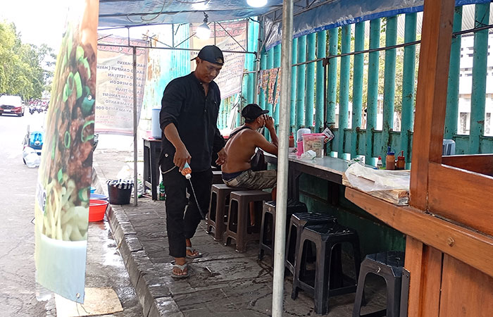 PENGUNJUNG BIAR NYAMAN: Lilik Pujiyanto menyemprotkan pewangi di lapaknya yang terletak di depan Depo Mandala Krida, kemarin (9/9).