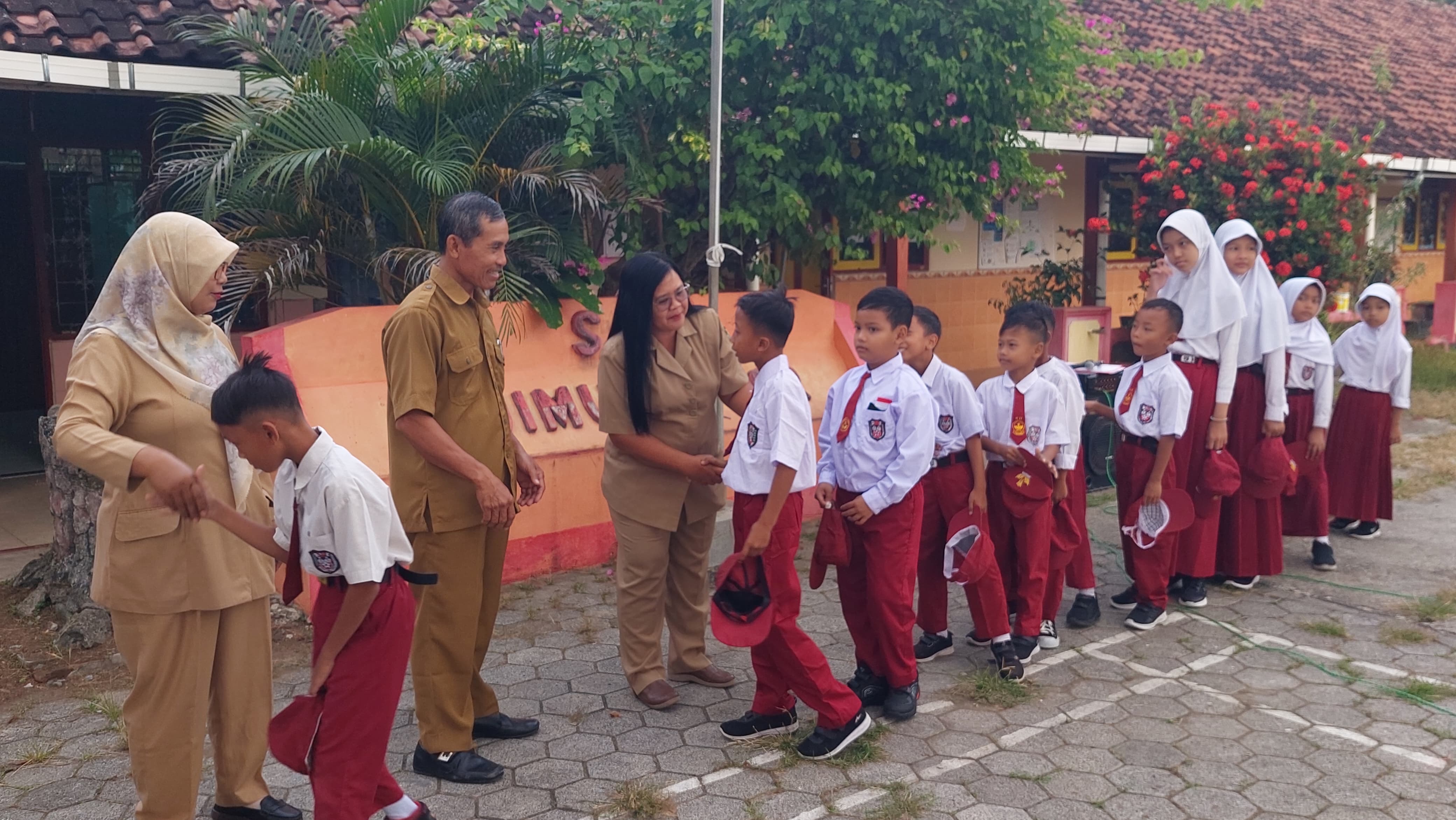 Siswa SD bersalaman dengan guru sebelum beraktivitas.