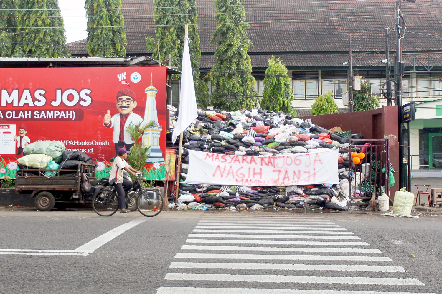 Pengguna jalan melintas di dekat spanduk bernada protes terhadap Pemkot Jogja yang dinilai gagal mengelola sampah di depo Jalan Brigjend Katamso, Kota Jogja, Selasa (16/9).