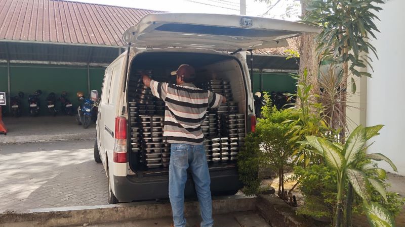 Petugas SPPG sedang menurunkan kotak makan MBG dari mobil untuk dibagikan ke siswa di SMAN 1 Sewon