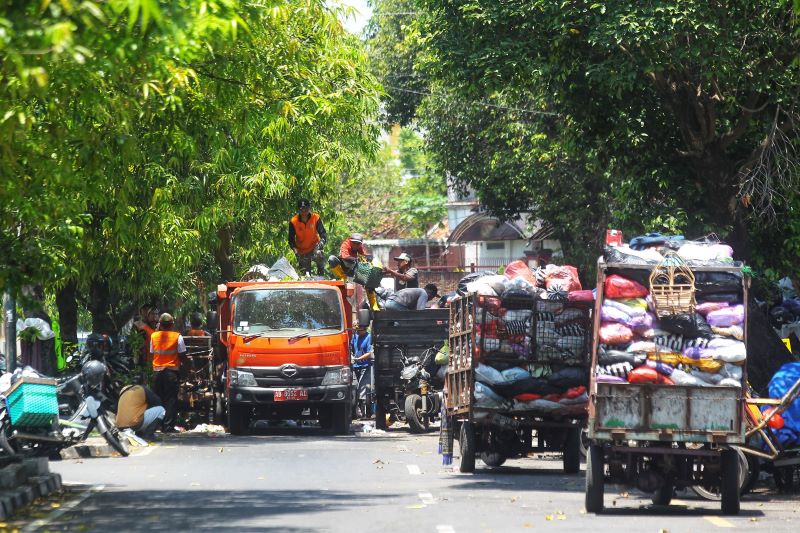 DIPINDAH: Petugas DLH Kota Jogja memindahkan tumpukan sampah dari gerobak ke armada pengangkut sampah di Depo Stadion Mandala Krida, Kota Jogja Selasa (23/9).