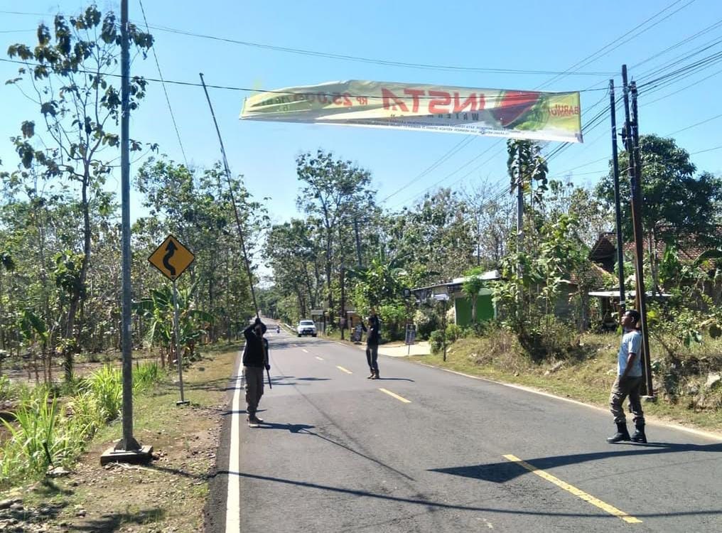 Satpol PP Gunungkidul sedang menertibkan baliho yang melintang di atas Jl. Lkr. Utara, Siyono Wetan, Kalurahan Logandeng, Kapanewon Playen, Kabupaten Gunungkidul pada Selasa (23/9).  &nbsp;