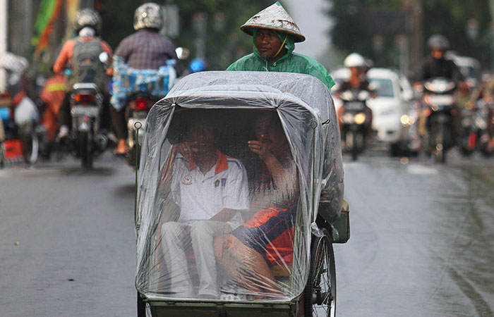 CUACA EKSTREM: Penumpang memandang keluar dari dalam becak yang dilapisi mantel saat hujan mengguyur Kota Jogja, kemarin (24/10).