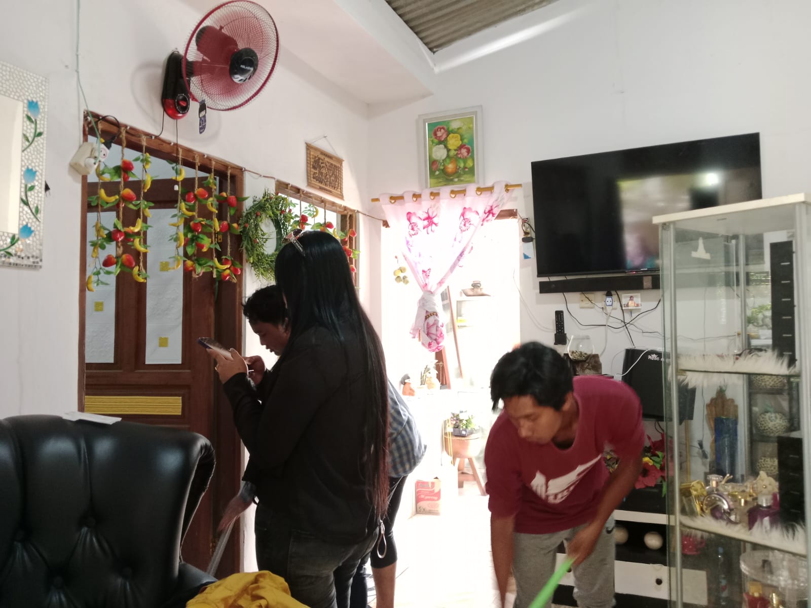 Seorang pria membersihkan darah yang bersimbah di laintai TKP rumah kontrakan korban.