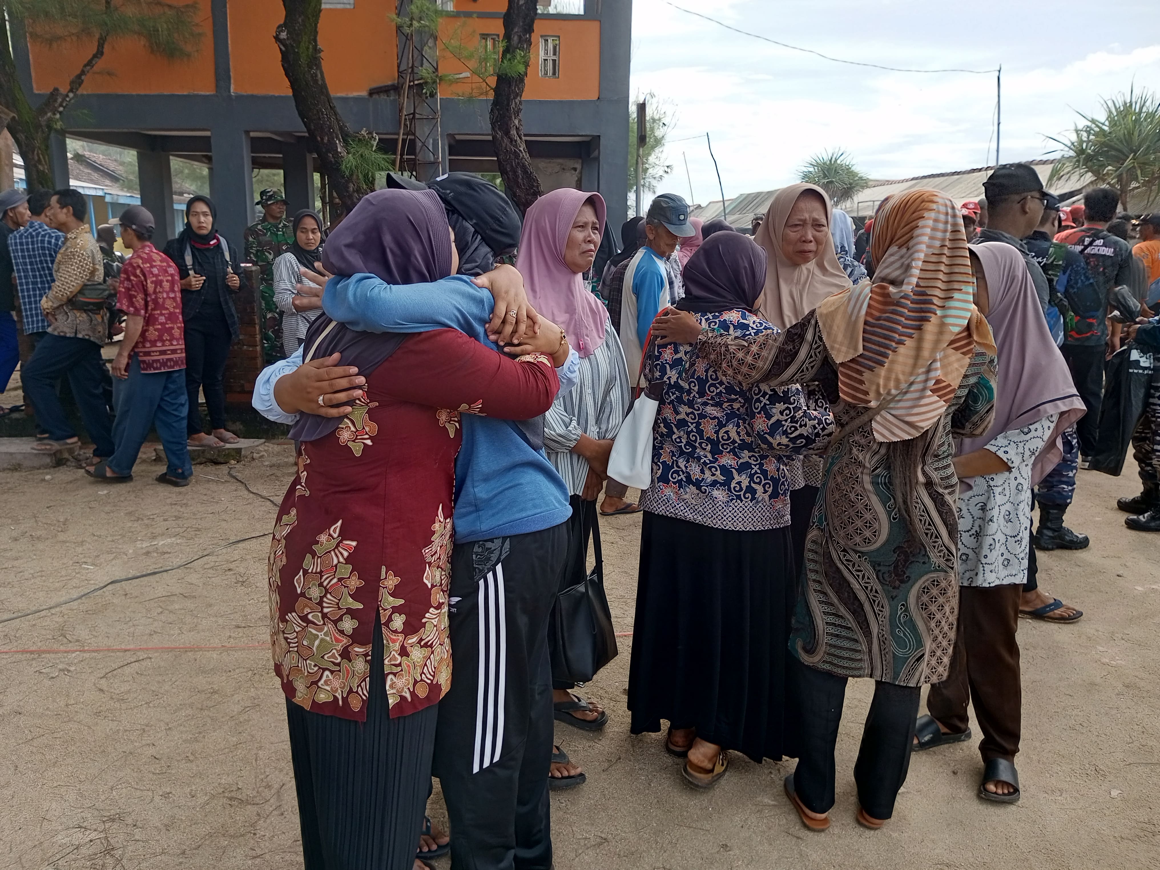 Ibu-ibu pedagang di Pantai Sepanjang saling berpelukan.