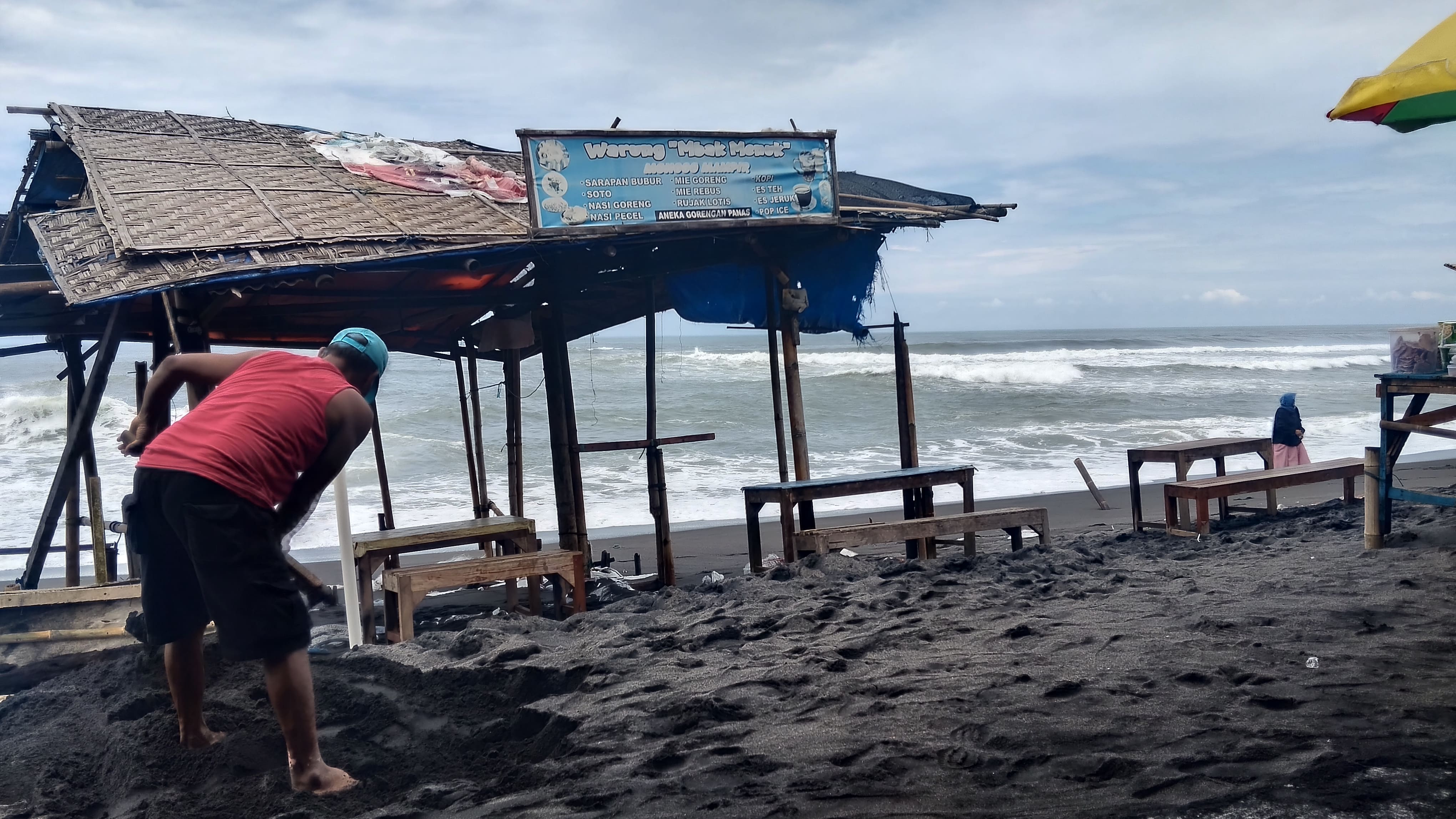 Tugiran sedang memperbaiki warungnya yang terkena gelombang tinggi Senin (10/11)&nbsp;  &nbsp;