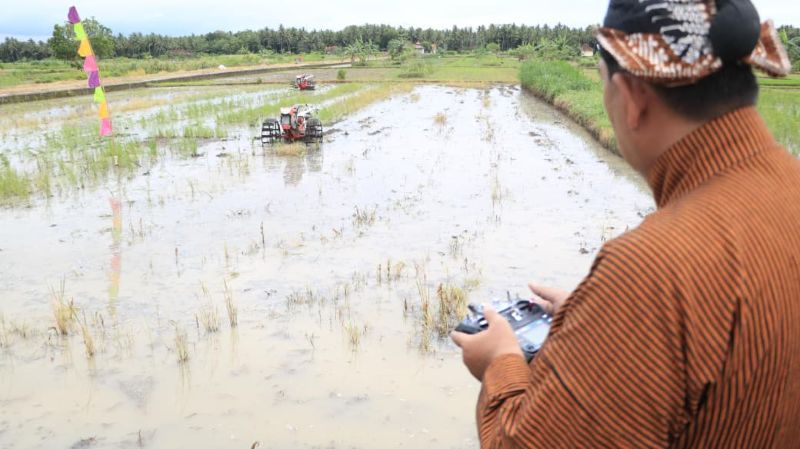 UJI COBA: Bupati Kulon Progo Agung Setyawan saat menjalankan traktor canggih yang dapat dikendalikan melalui remot kontrol, Jumat (21/11/2025).