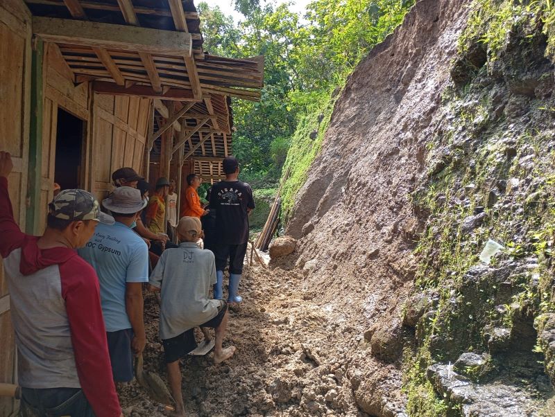 TERDAMPAK: Warga bergotong royong membersihkan material longsoran di kawasan Perbukitan Menoreh.