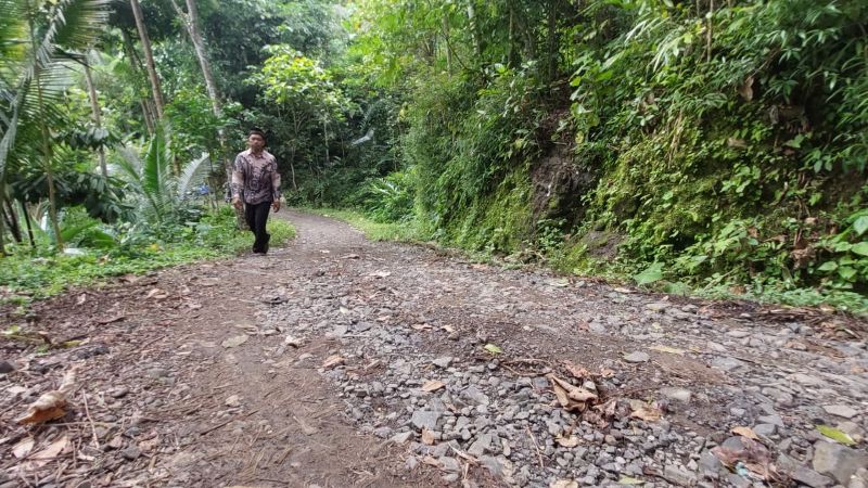 Seorang warga berjalan kaki menapaki Jalan Branti-Gondangan, Padukuhan Sonya, Kalurahan Jatimulyo, Kapanewon Girimulyo, Kulon Progo yang kondisinya rusak berat.