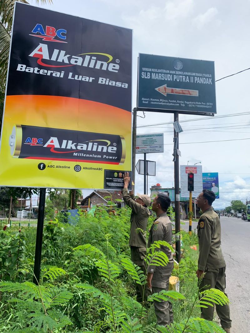 SEBELUM EKSEKUSI: Personel Satpol PP Kabupaten Bantul menempelkan surat peringatan. Jika dihiraukan, satpol PP akan mengambil tindakan tegas.