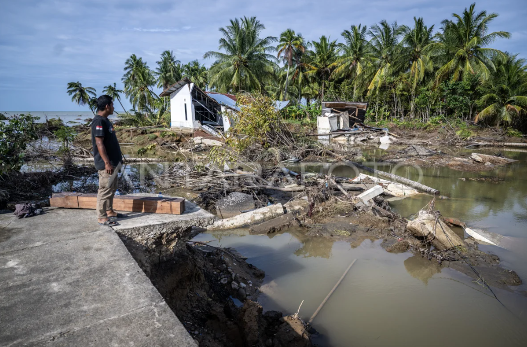 Warga melihat jalan yang terputus akibat banjir di Desa Kuala Keureuto, Aceh Utara, Aceh, Senin (8/12/2025).