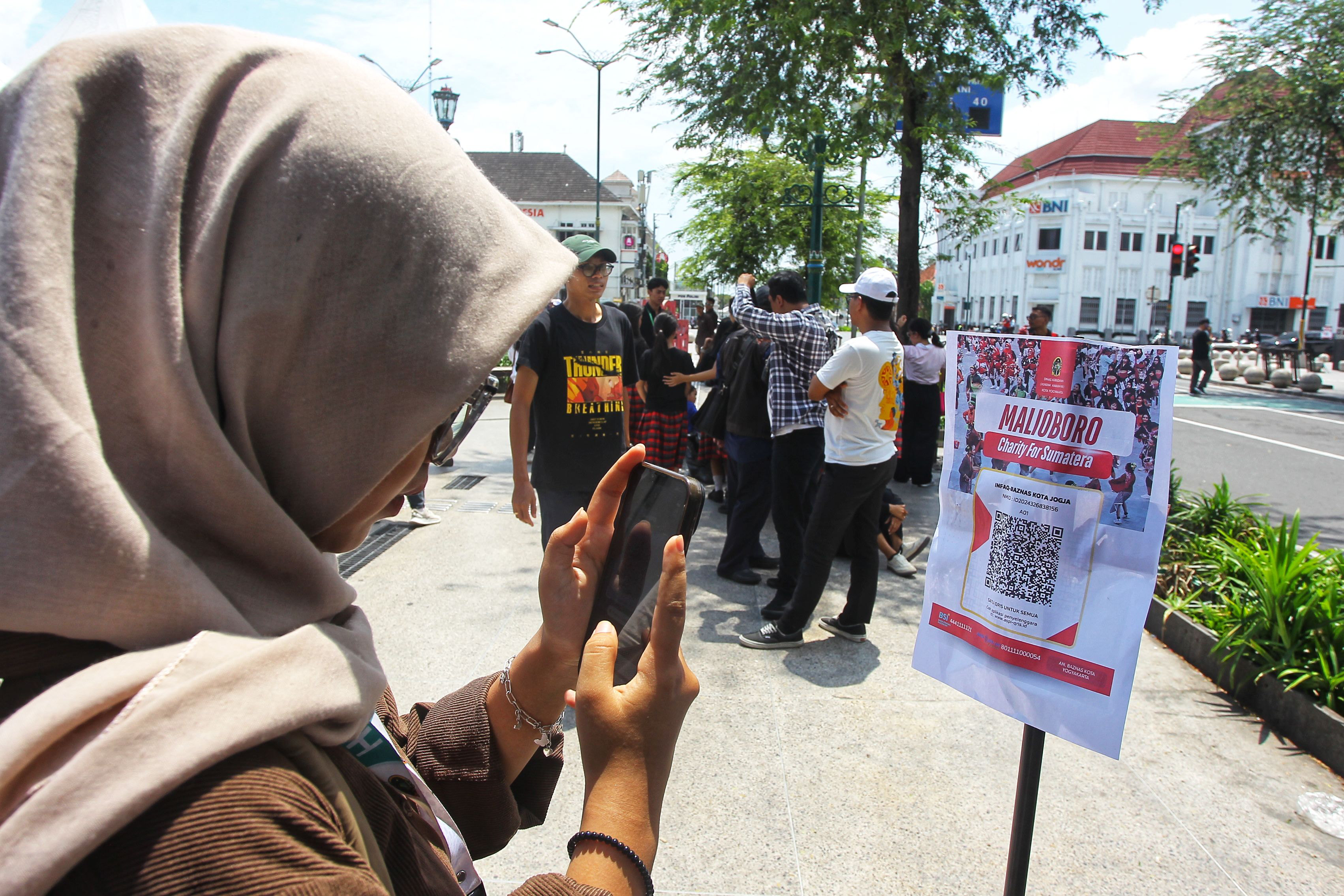 Warga berdonasi menggunakan metode pembayaran QRIS saat digelar Malioboro Charity for Sumatera, di kawasan Titik Nol Kilometer, Kota Jogja, kemarin (10/12). Kawasan Malioboro tak hanya berfungsi sebag
