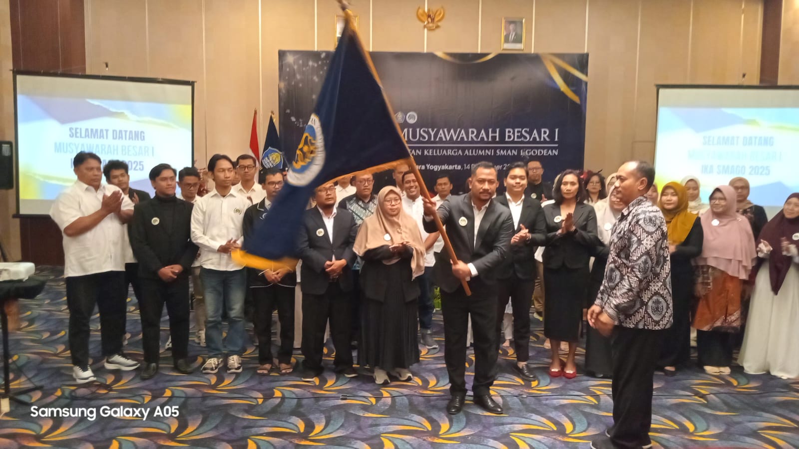 AKLAMASI: Adit Setiawan mengibaskan pataka IKA SMAGO usai terpilih sebagai ketua umum dalam musyawarah besar pertama di Hotel Tara Jogja Minggu (14/12).