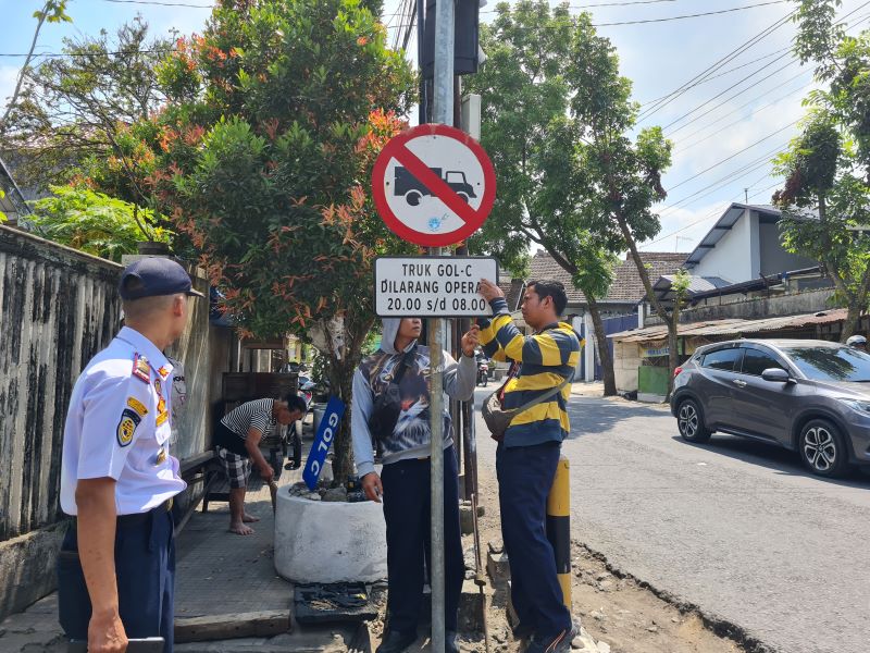 PENANDA: Petugas memasang papan informasi terkait jam operasional truk golongan C di Simpang Empat Sayangan, Muntilan.