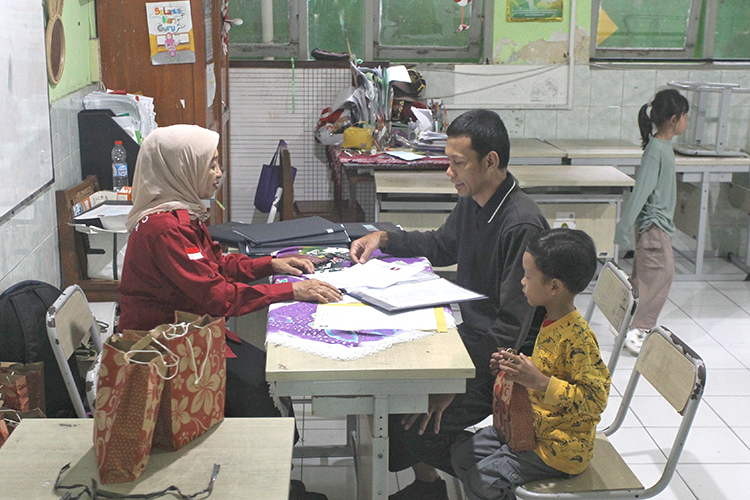 Guru berbincang dengan orang tua murid saat pembagian rapor di SD Negeri Jetisharjo, Kota Jogja, Jumat (19/12/2025).