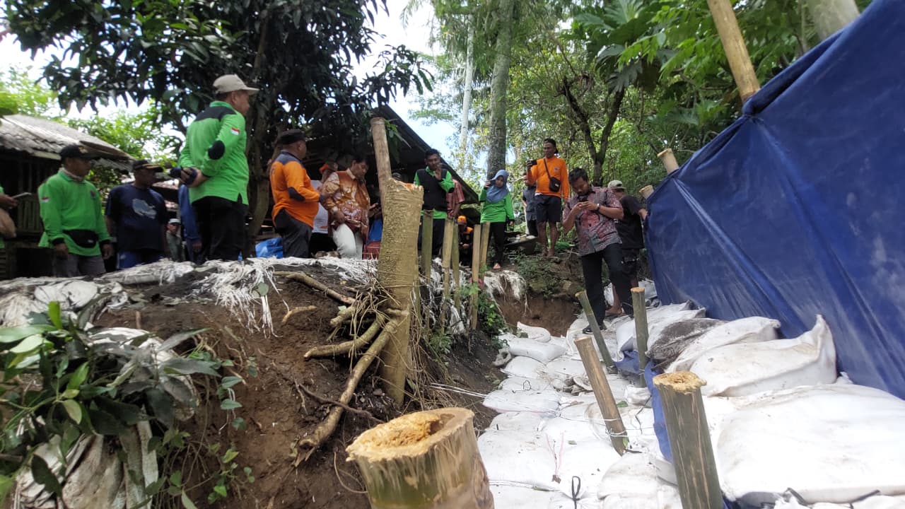 GOTONG ROYONG: Warga mengangkut geobag yang telah diisi pasir dan ditumpuk sebagai tanggul sungai.