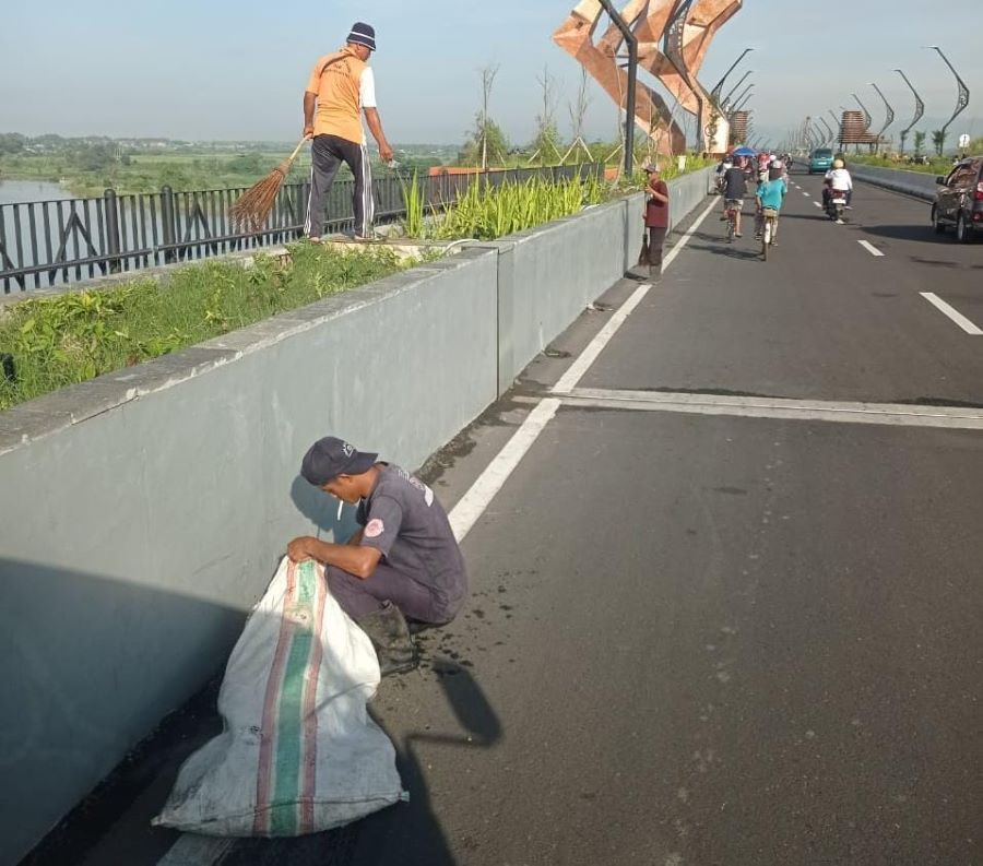 MEMBERSIHKAN: Petugas kebersihan sedang membersihkan sampah yang berada di Jembatan Kabanaran Minggu (21/12)