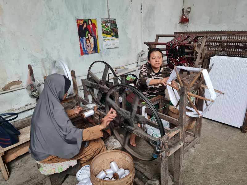 TEKUN: Proses pembuatan sarung tenun Cap Botol Terbang masih menggunakan alat tradisional.