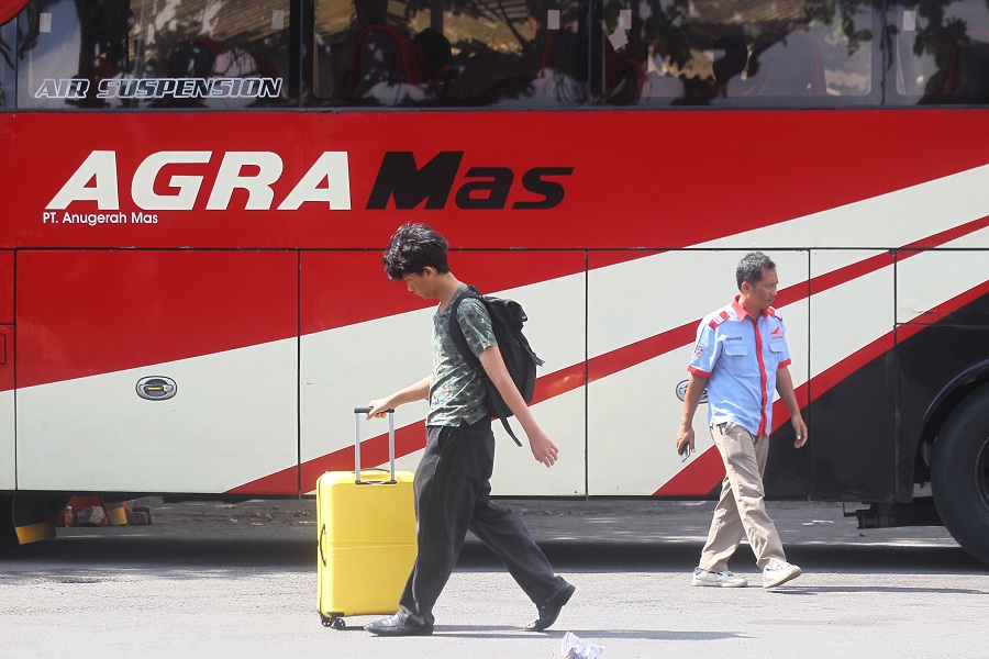 Calon penumpang melintas di dekat armada bus di Terminal Jombor, Sleman, Kamis (22/12/2025).