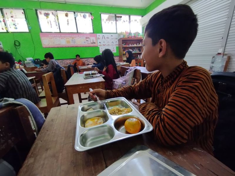MENIKMATI: Siswa sekolah dasar memakan menu MBG dengan lahap.&nbsp;