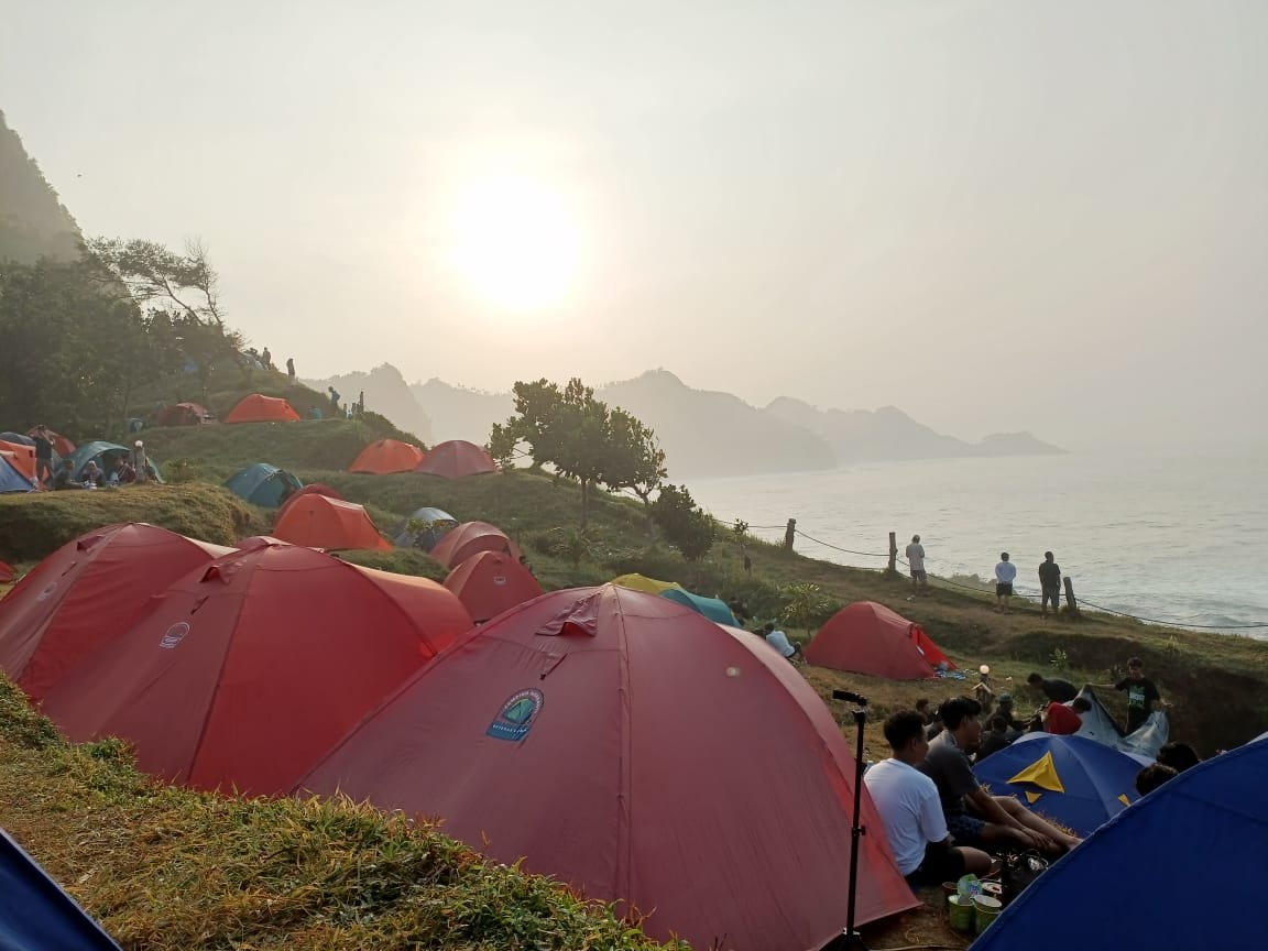 Pegunjung Pantai Menganti menikmat keindahan panorama matahari terbit dari balik tenda. (M Hafied/Radar Jogja)