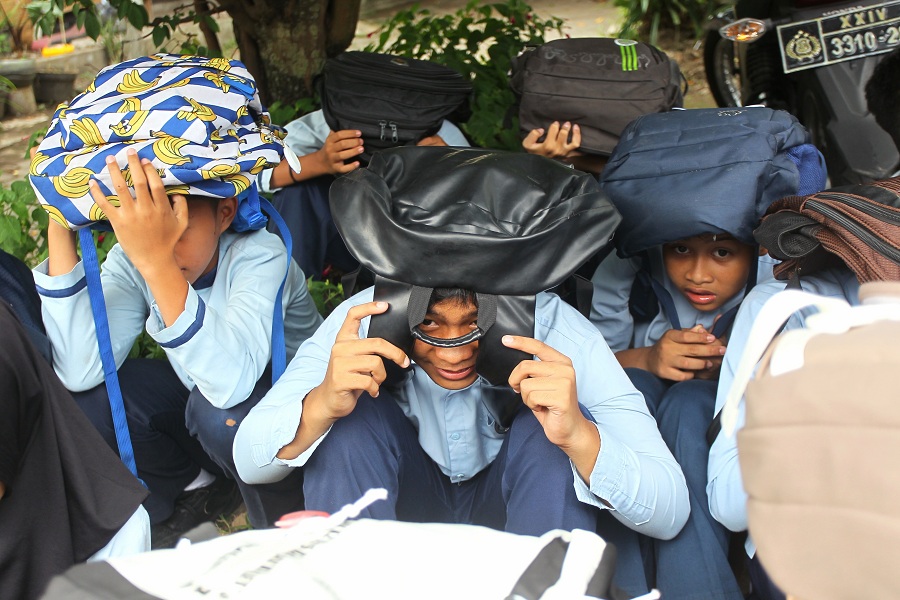 Pelajar SD Negeri Gedongkuning melindungi kepala mereka menggunakan tas saat terjadi gempa bumi dalam simulasi penanganan bencana dan penutupan pelatihan SPAB, Kota Jogja Jumat (9/1/2026).